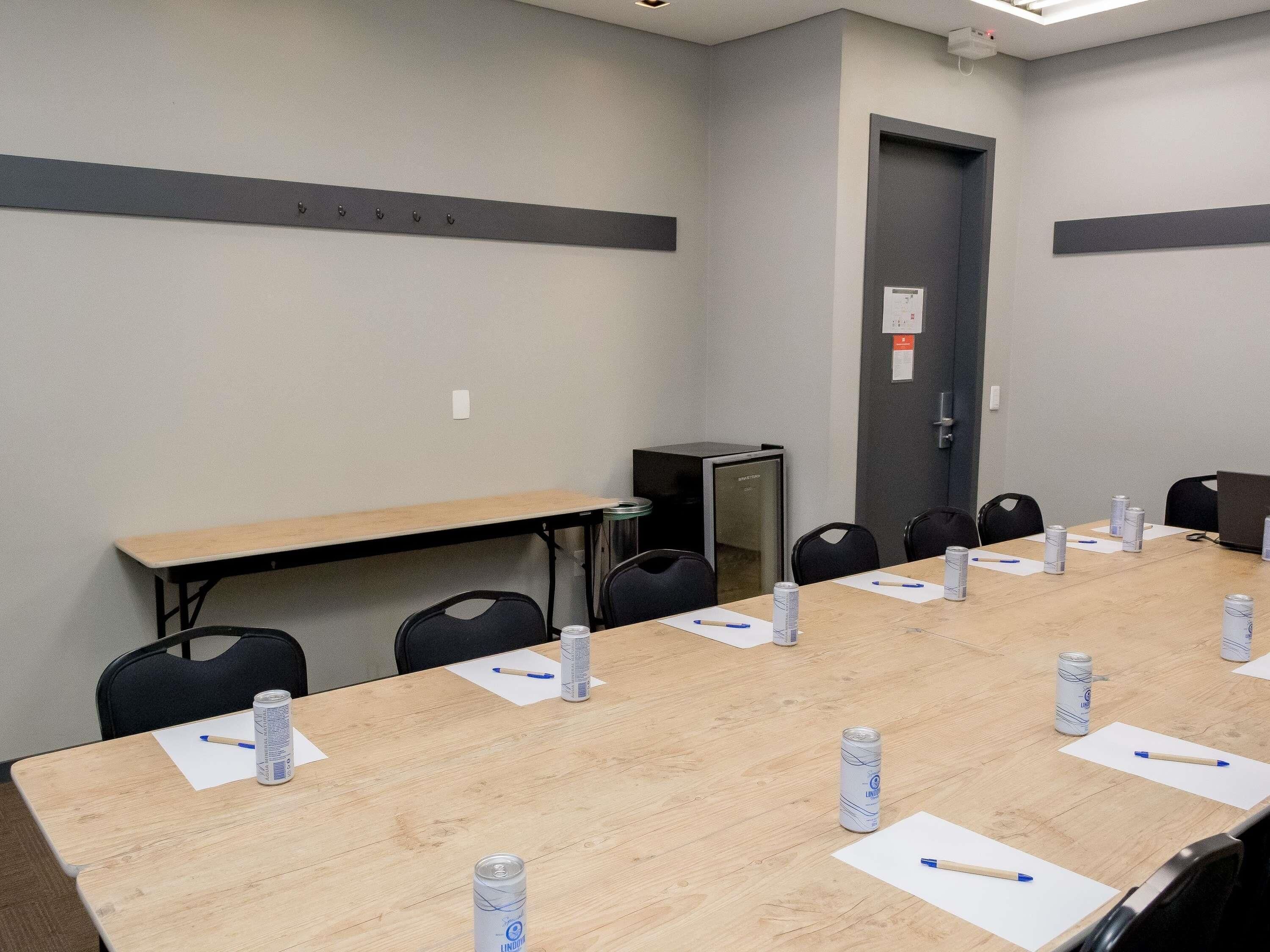 Une salle de conférence avec une longue table, des chaises et une porte.