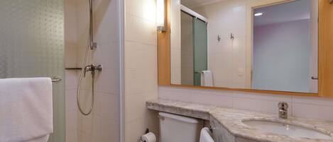 A bathroom with a shower, toilet, sink, and a mirror.