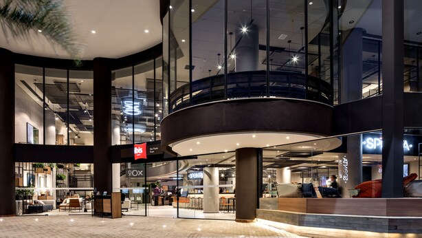 Een modern winkelgebied binnen met glazen balustrades, een centraal atrium en diverse winkelbedrijven.