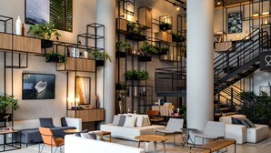 Een modern interieur met een hoge plafond, zichtbare balken en een centrale trap.