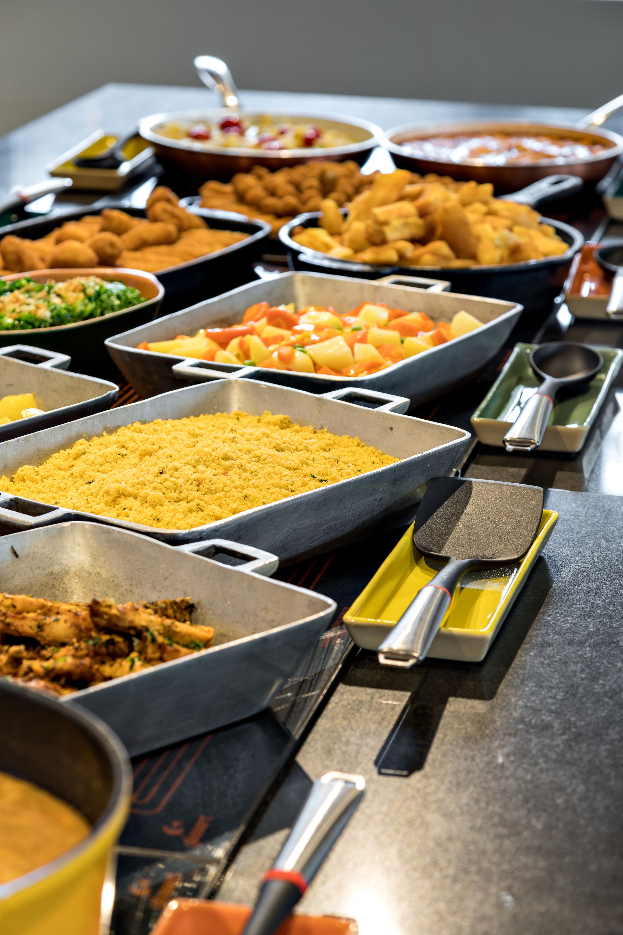 Una mesa de buffet con diversos platos, entre ellos, frituras, ensaladas y arroz.