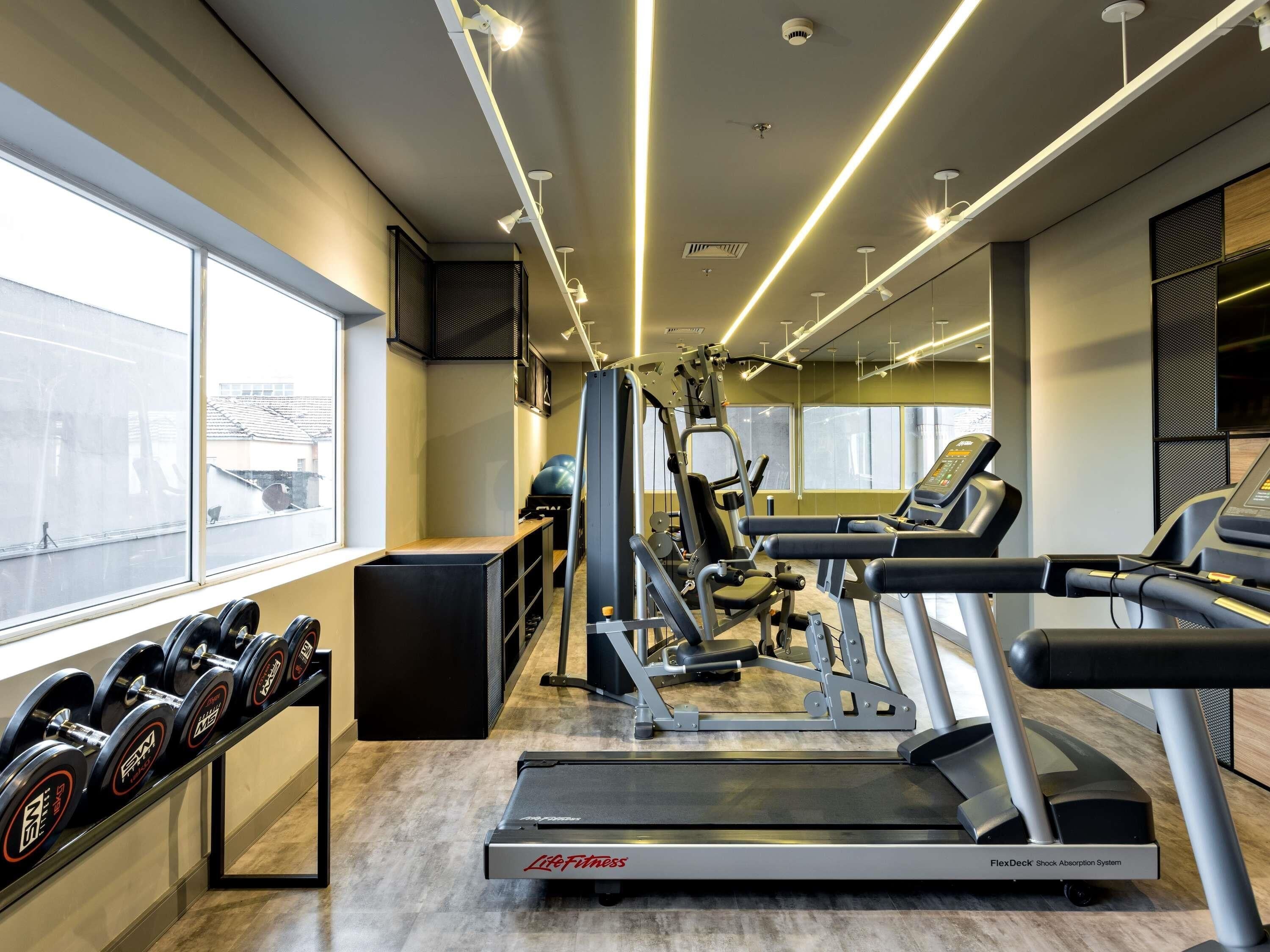 Ein Fitnessstudio mit Laufbändern, Kurzhanteln und Krafttrainingsgeräten.