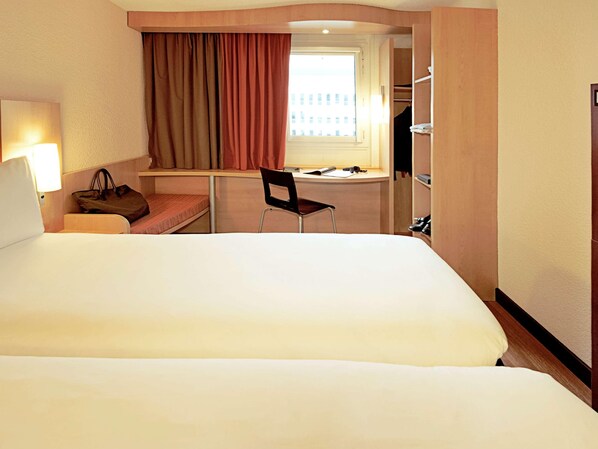 Une chambre d’hôtel avec un grand lit, un bureau, une chaise, une lampe et une armoire.
