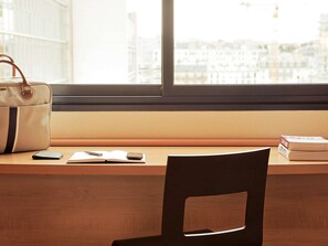 Un bureau en bois, une chaise noire, un sac à main blanc, un téléphone intelligent, un carnet et un stylo.