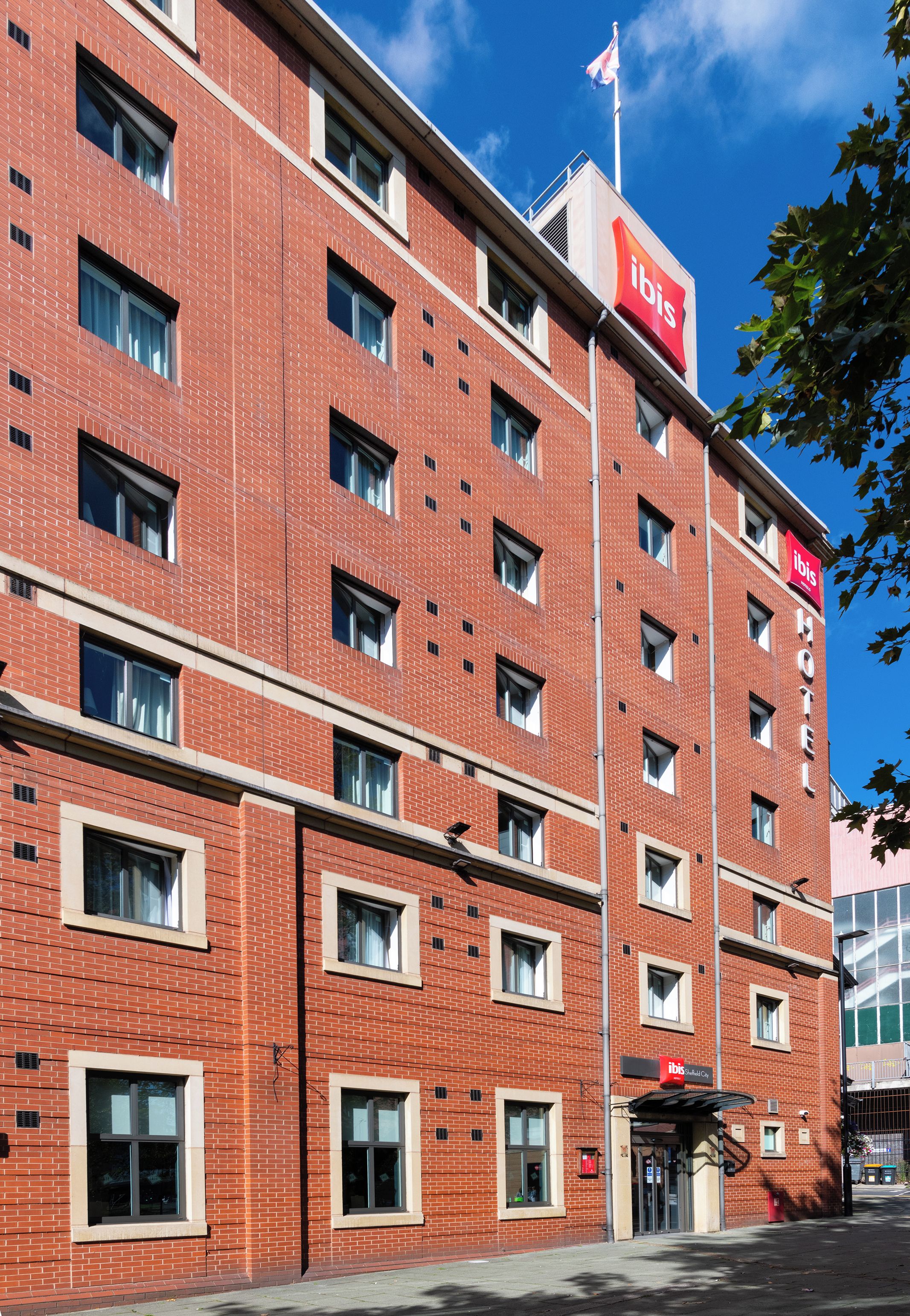 Un hôtel aux murs de briques rouges, doté de nombreuses fenêtres et d’une enseigne « ibis » bien visible.