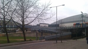 A pedestrian walkway with a bridge, a stadium, and a tram. - ibis Sheffield City (Sheffield)