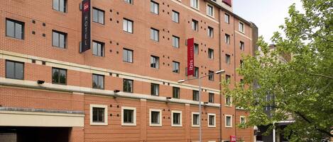 A multi-story hotel with a brick facade, multiple windows, and a visible entrance.