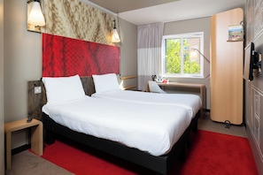 A hotel room with a large bed, a desk, a chair, a wardrobe, and a window with a view of greenery. - ibis Sheffield City (Sheffield)