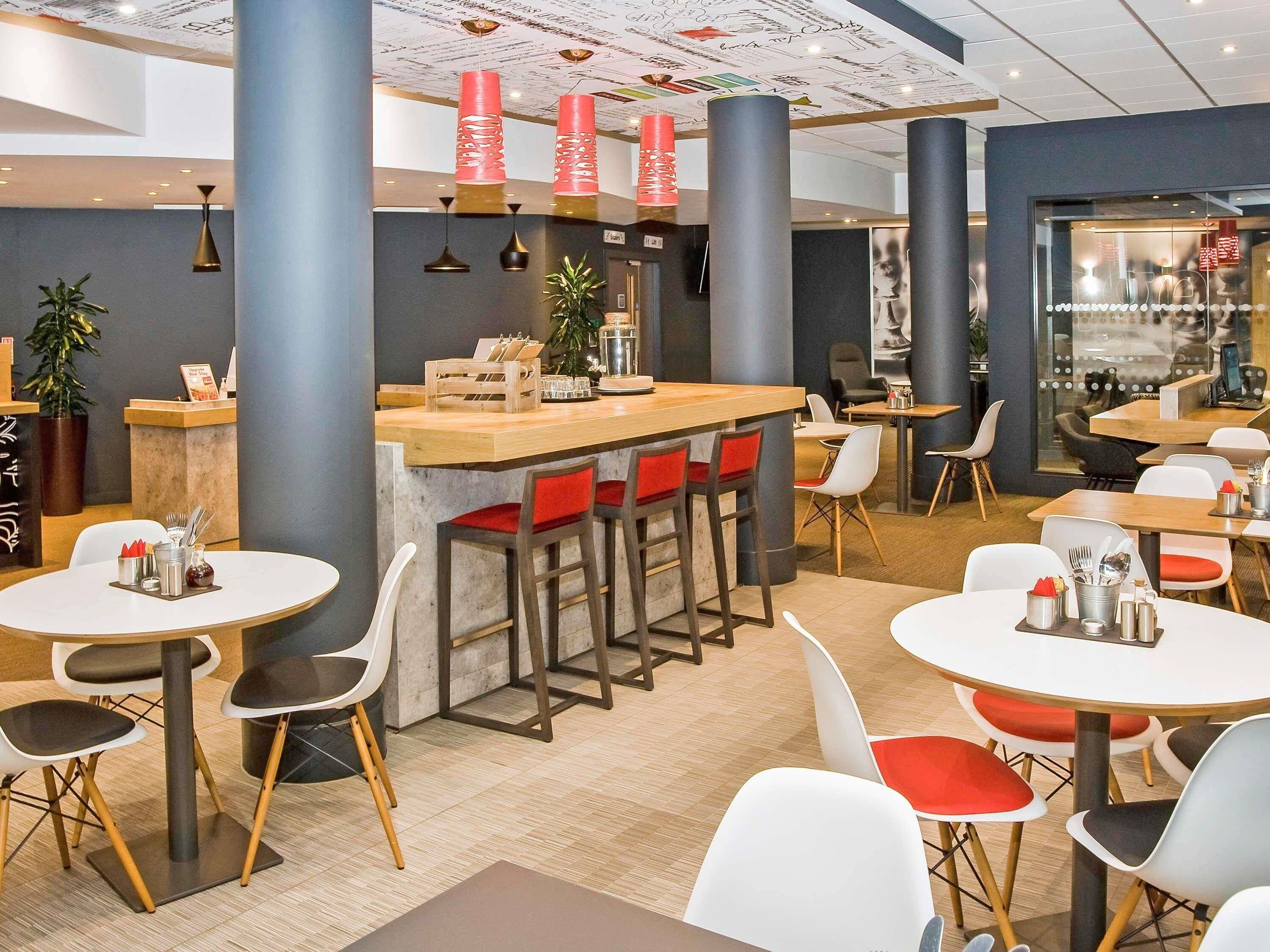 A modern restaurant interior with round tables, bar seating, and a counter.