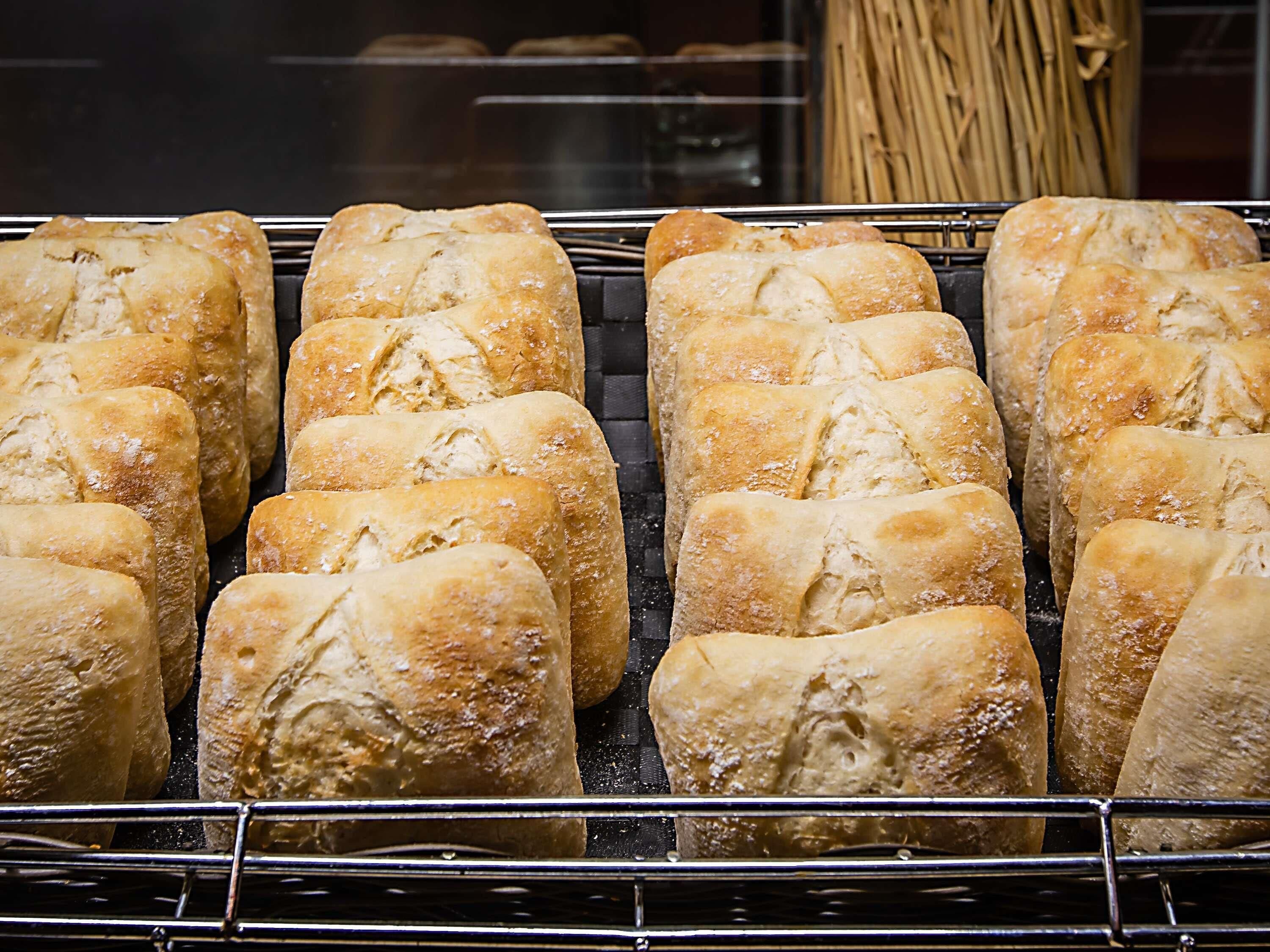 Mostrador de panadería con hogazas de pan recién horneadas dispuestas en una rejilla.