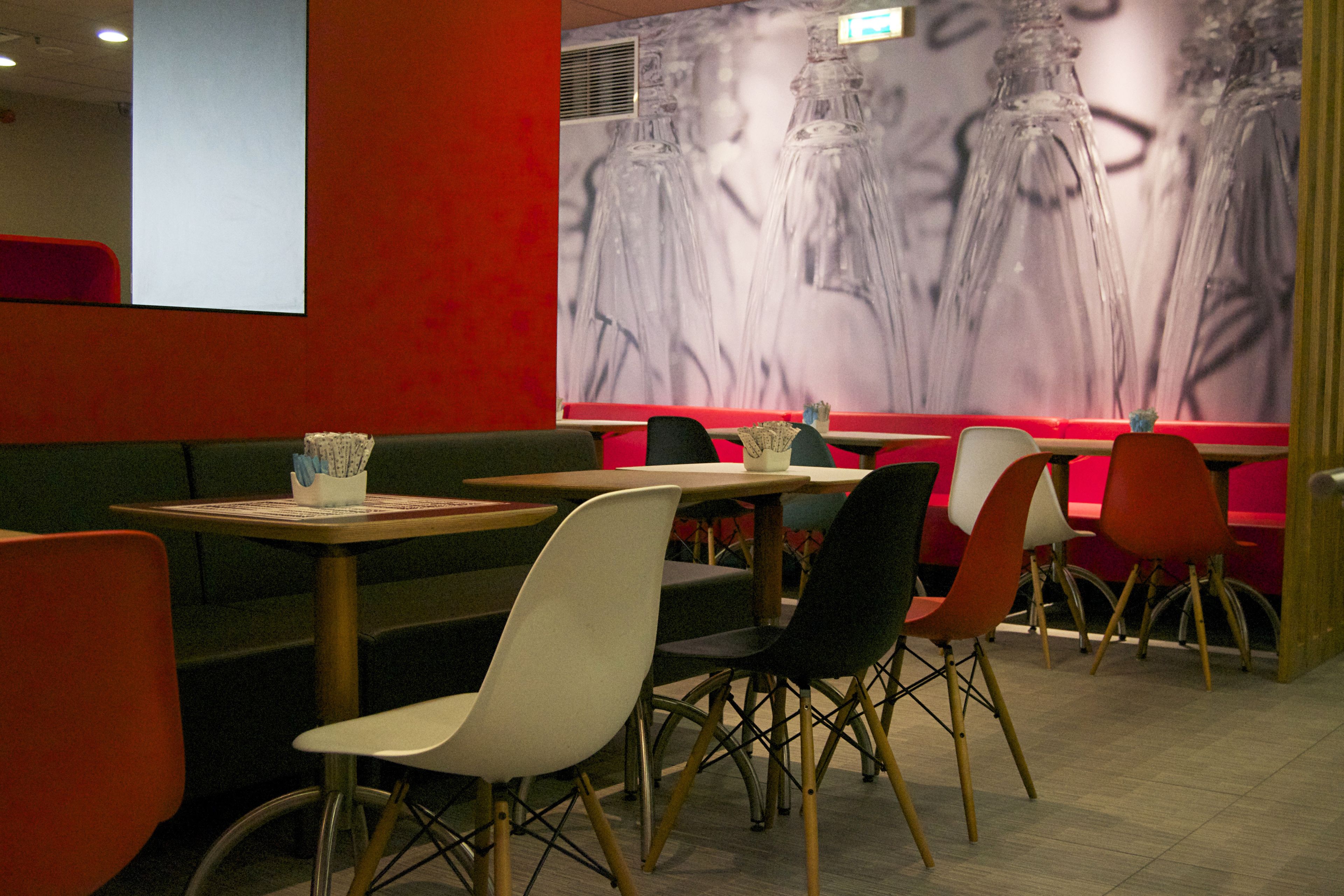 Un interior de restaurante con cabinas y mesas, un gran mural en la pared y una pared de acento roja.