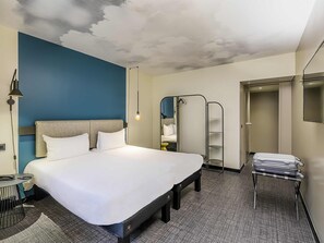 Hotellihuone, jossa on suuri sänky, työpöytä, tuoli, vaatekaappi ja peili.