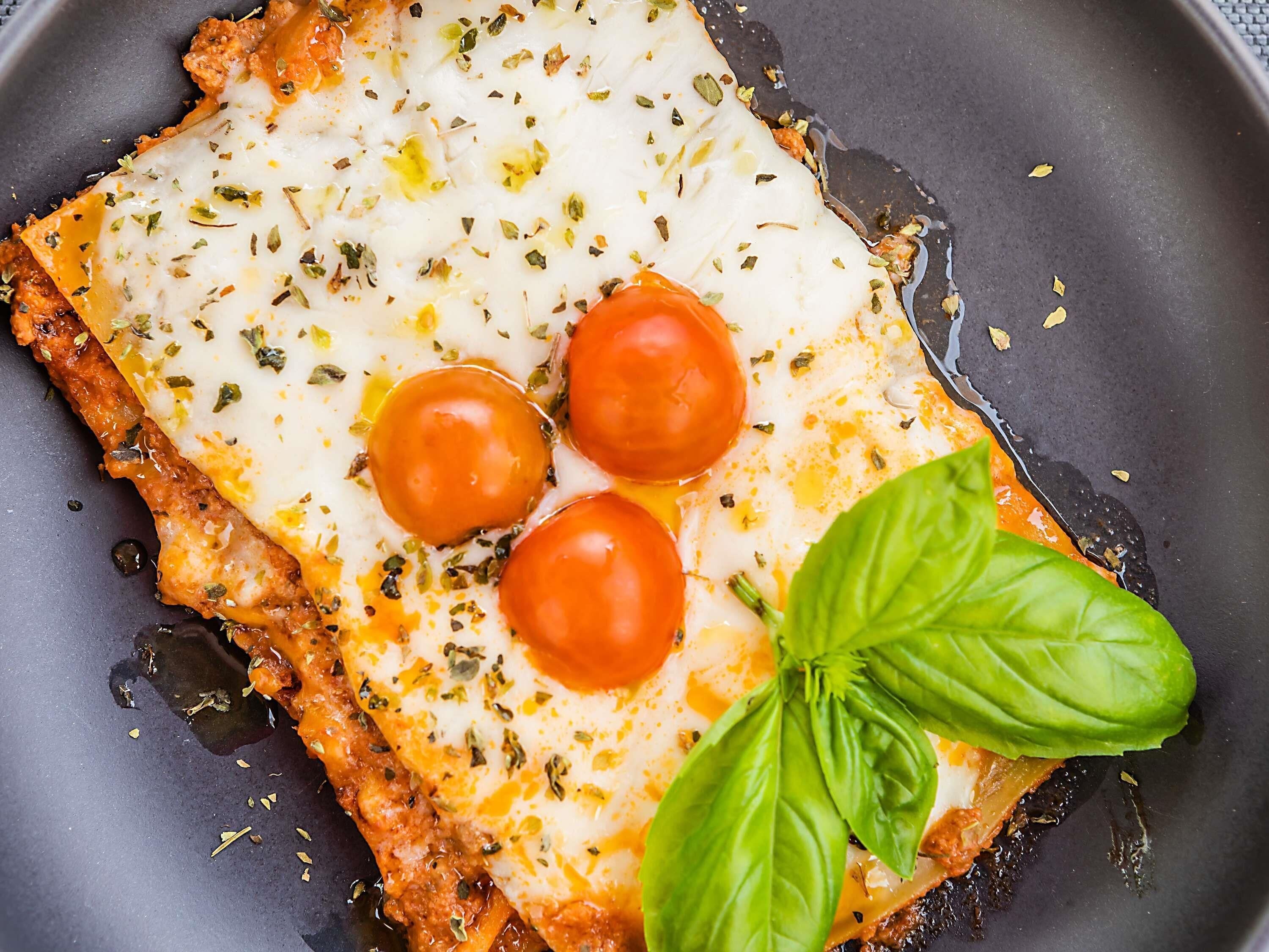 Primer plano de un plato con queso, tomates y albahaca en una sartén.
