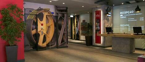 A reception area with a large mechanical sculpture, a reception desk, and a wall with a price list.