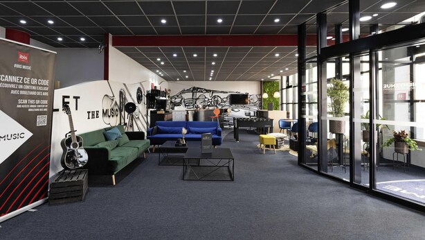 A modern lounge area with sofas, a coffee table, and a wall mural. - ibis Paris Pantin Eglise (Pantin)