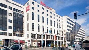 A modern hotel with a prominent 'ibis Hotel' sign, multiple floors, and a clear sky. - ibis Paris Pantin Eglise (Pantin)