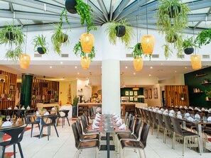 A spacious dining area with multiple tables and chairs, hanging plants, and a modern interior design. - ibis Antananarivo Ankorondrano (Antananarivo)