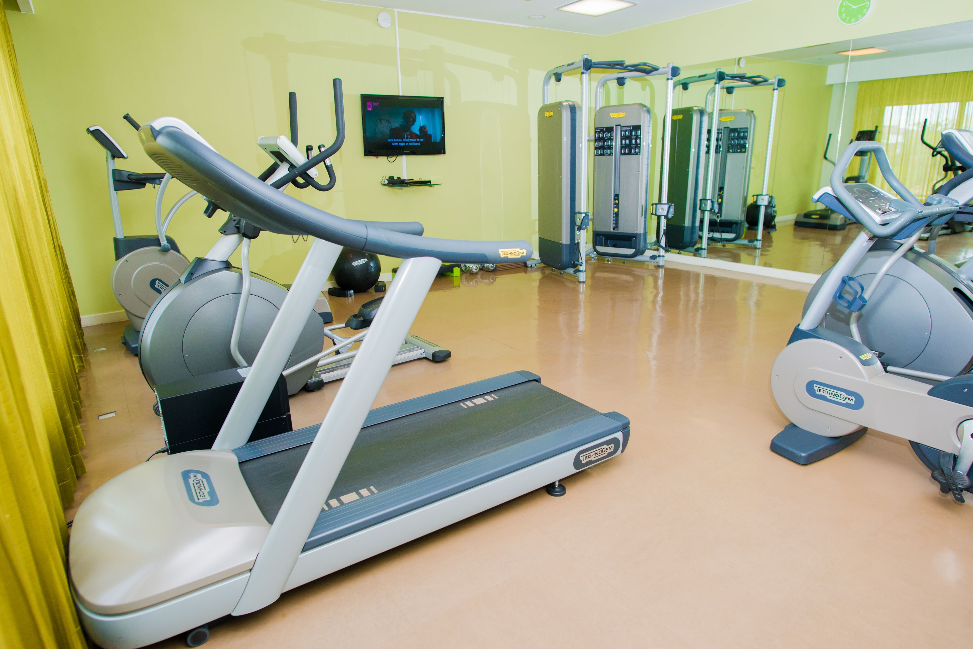 Un gimnasio con cintas de correr, elípticas y equipo de pesas.