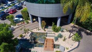 A modern building with a circular design, surrounded by a landscaped garden with a small pond and steps leading to the entrance. - ibis Antananarivo Ankorondrano (Antananarivo)