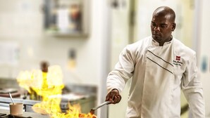 A chef in a white uniform cooking on a stove with flames. - ibis Antananarivo Ankorondrano (Antananarivo)