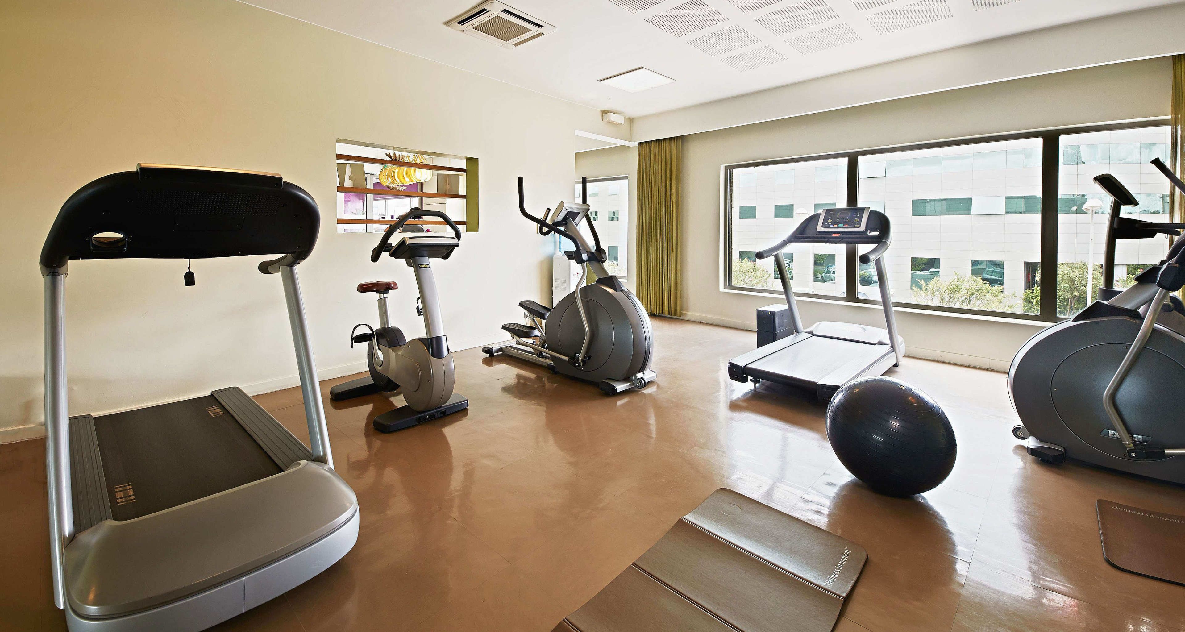 Un gimnasio con cintas de correr, elípticas y una bicicleta estática.