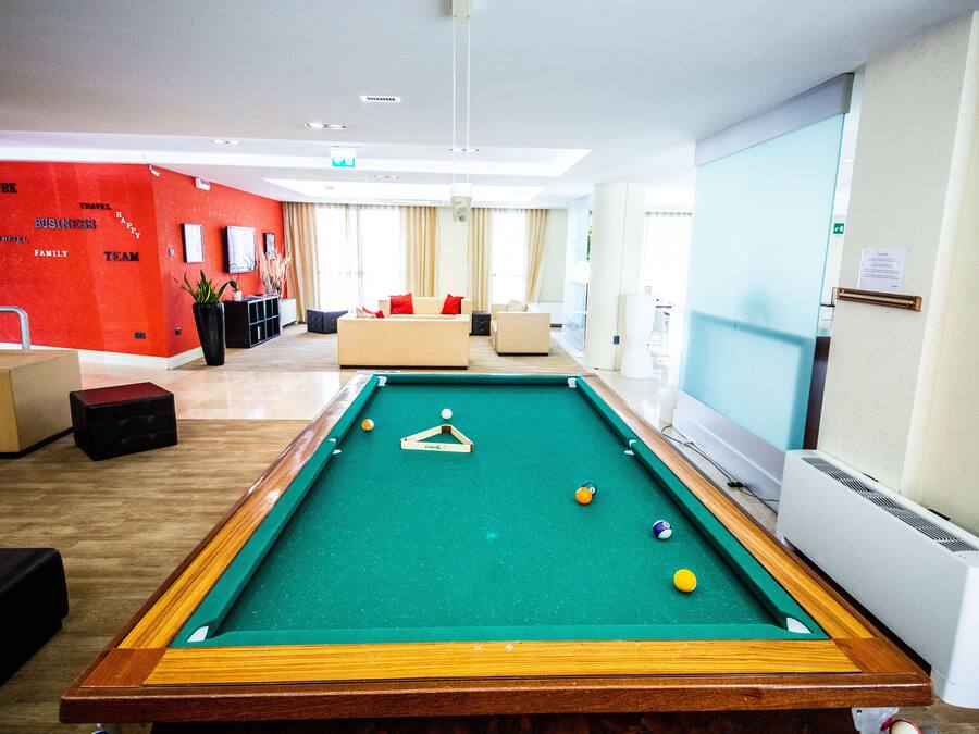 A pool table in a hotel lobby with a red wall featuring words like "WORK," "BUSINESS," "TRAVEL," "FAMILY," and "TEAM."