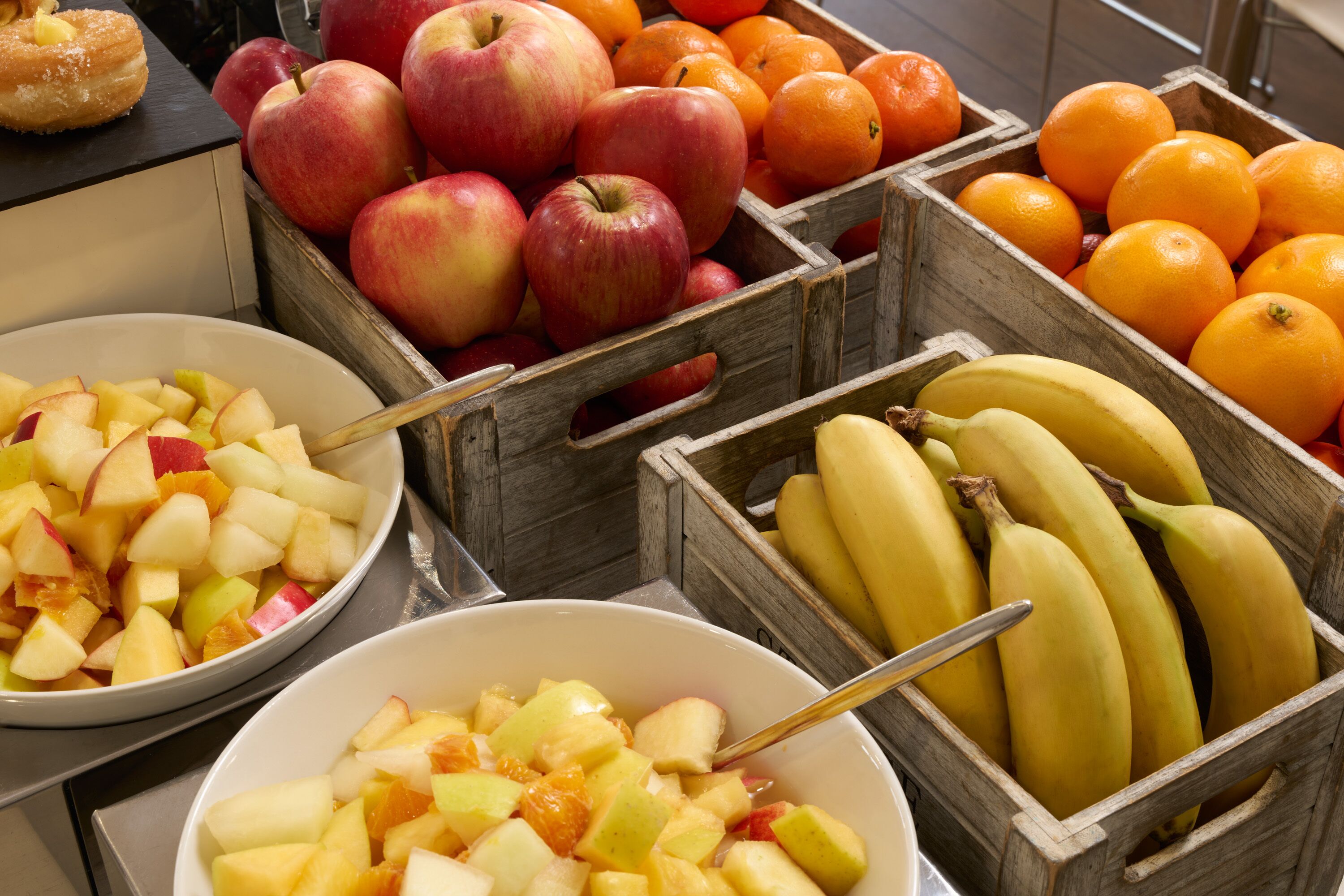 A fruit display with apples, oranges, and bananas in wooden crates.