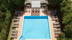 An aerial view of a swimming pool surrounded by lounge chairs and a covered seating area. - Hotel Roma Tor Vergata (Rome)