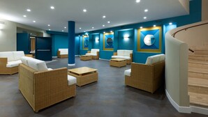 A spacious lobby with wicker furniture and a curved staircase. - Hotel Roma Tor Vergata (Rome)