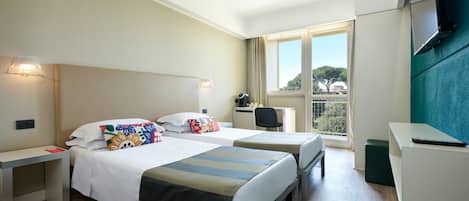 Habitación de hotel con dos camas, un escritorio, una silla, un televisor y una ventana con vistas.