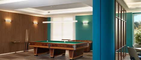 A pool table in a room with teal walls, a wooden panel wall, and a large blue pillar.