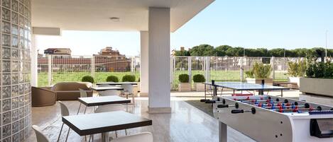An outdoor patio with tables and chairs, a foosball table, and a tennis table.