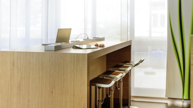 Una cocina moderna con encimera de madera, taburetes de bar y un ordenador portátil.