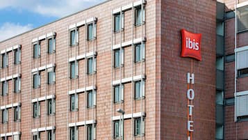 Un bâtiment d'hôtel avec une enseigne rouge « ibis », de nombreuses fenêtres et une façade en briques.