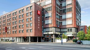 Un hotel moderno con fachada de ladrillo rojo, numerosas ventanas y un llamativo logotipo de 'ibis'.