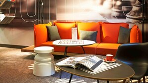 A modern lounge area with a sofa, a coffee table, and a magazine. - Hôtel ibis Strasbourg Centre Petite France (Strasbourg)