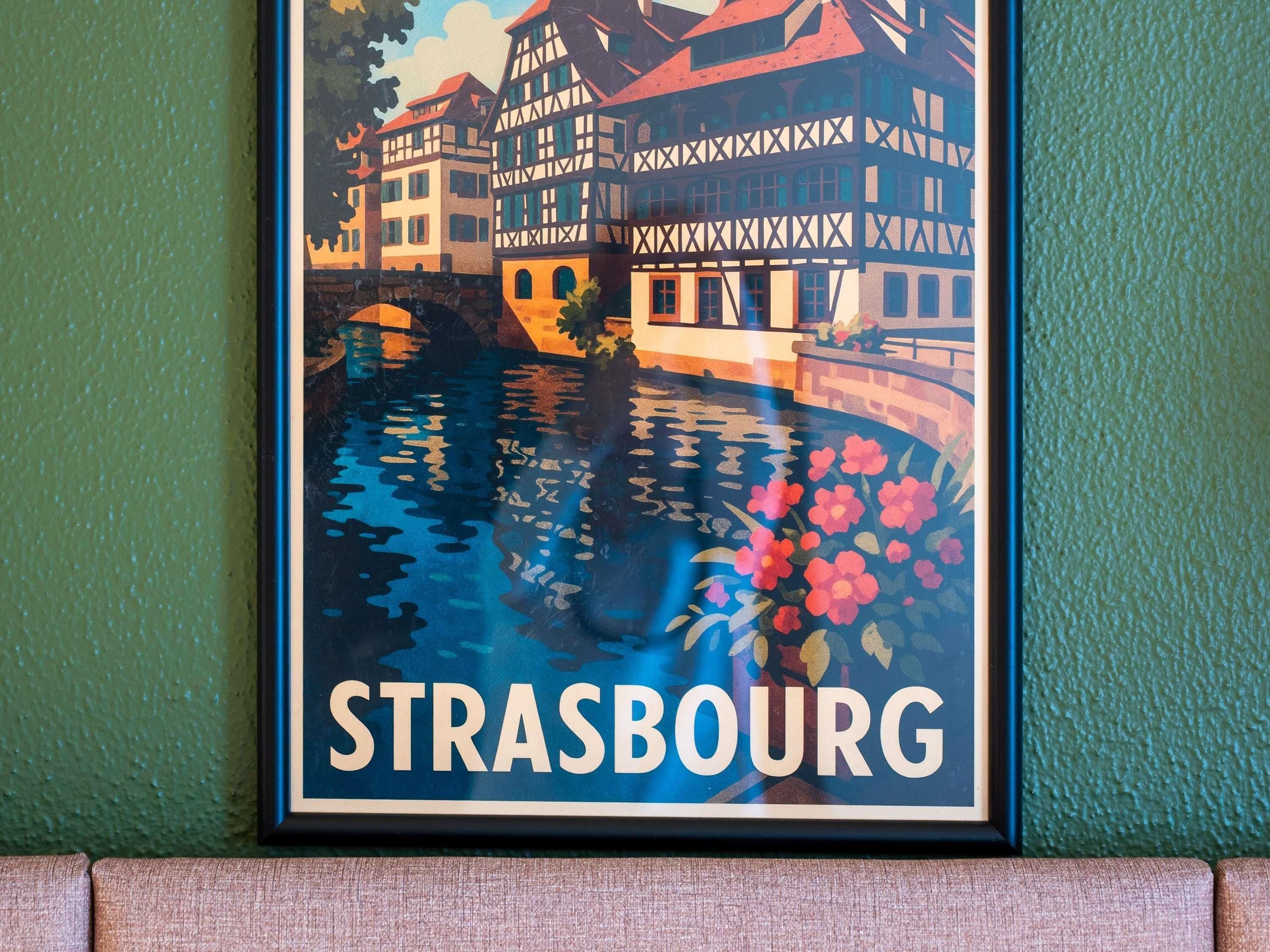 Un cartel enmarco de Estrasburgo, con un río y edificios.