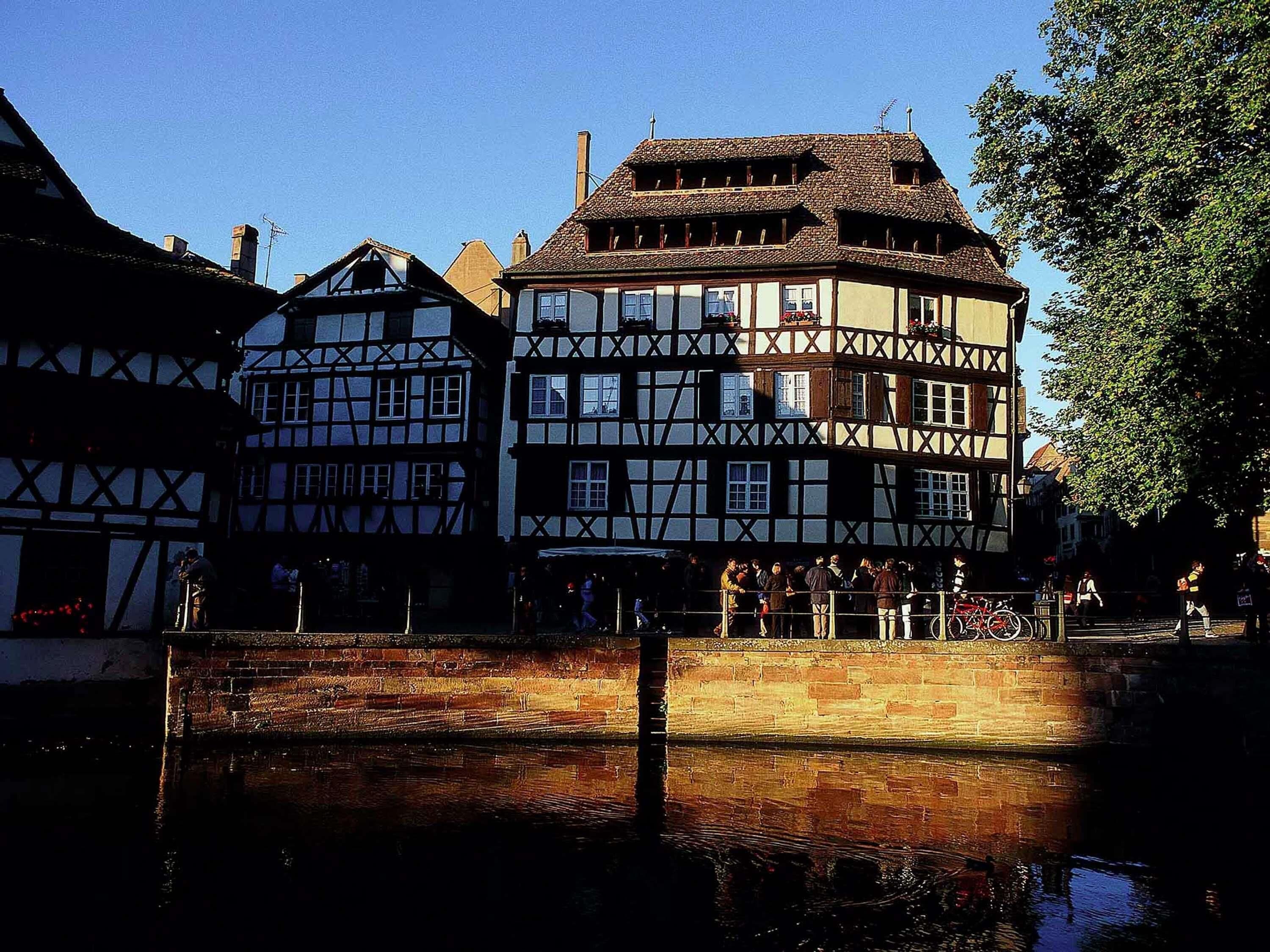 Ein traditionelles Fachwerkhäuschen mit einem Fluss davor.