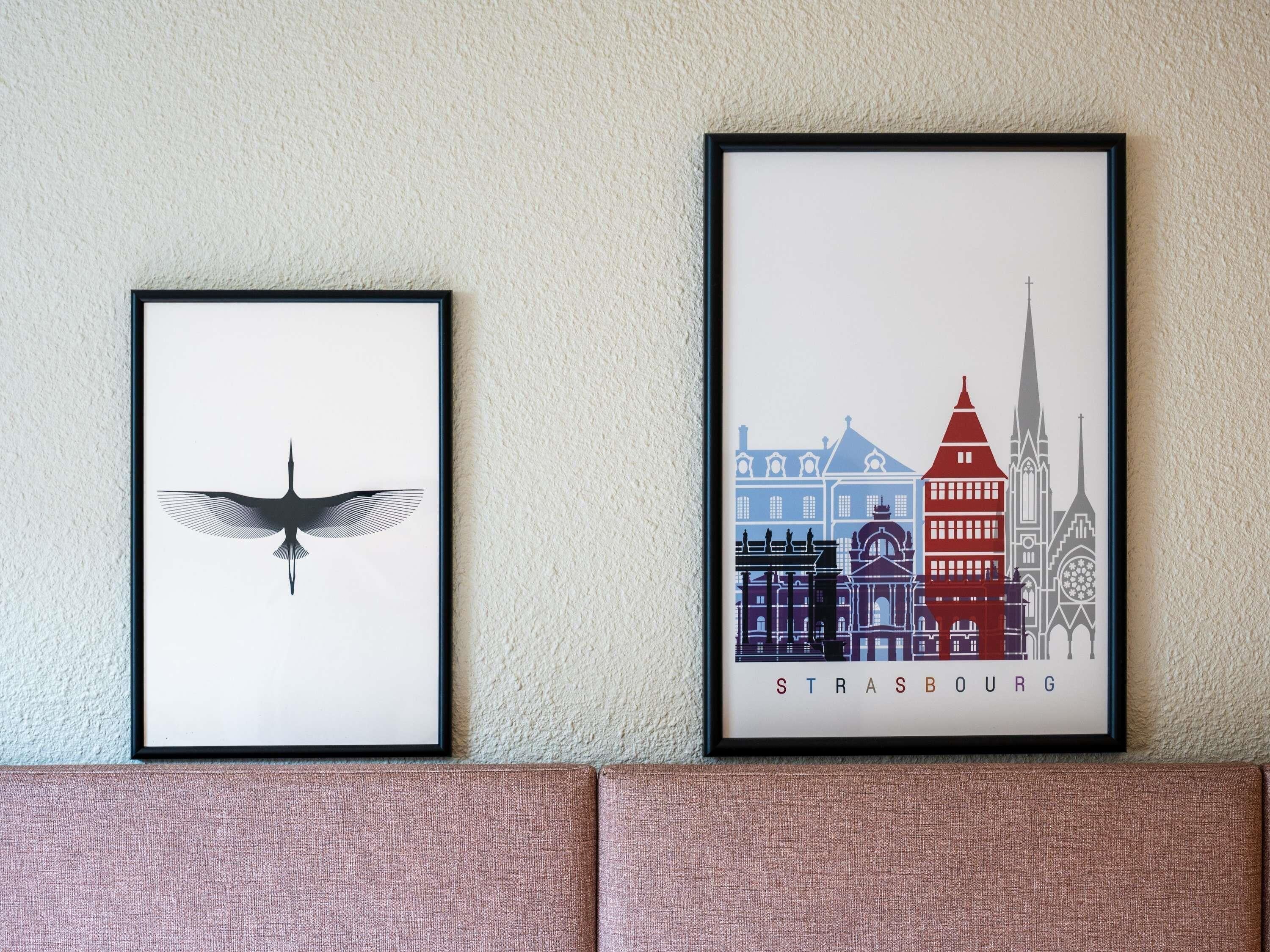 Twee kunstwerken in lijsten aan een muur.