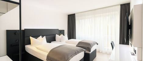 Habitación de hotel con dos camas, un escritorio y un televisor.