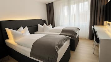 Une chambre d’hôtel avec deux lits, un bureau et une chaise.