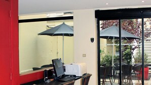 A room with a desk, computer, and two chairs. There are two umbrellas outside the door. - New Hôtel Saint Lazare (Paris)