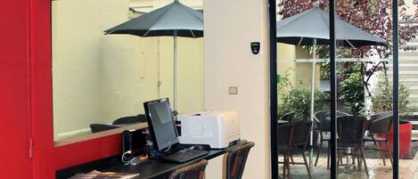 Une pièce comprenant un bureau, un ordinateur et deux chaises. Il y a deux parapluies devant la porte.