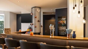 A modern bar area with a counter, bar stools, a drink menu, and a decorative pineapple. - Vienna House Easy by Wyndham Amberg (Amberg)