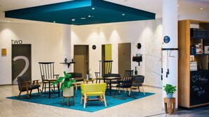 A modern lounge area with multiple seating options, a chalkboard with motivational writing, and a bookshelf. - Vienna House Easy by Wyndham Amberg (Amberg)