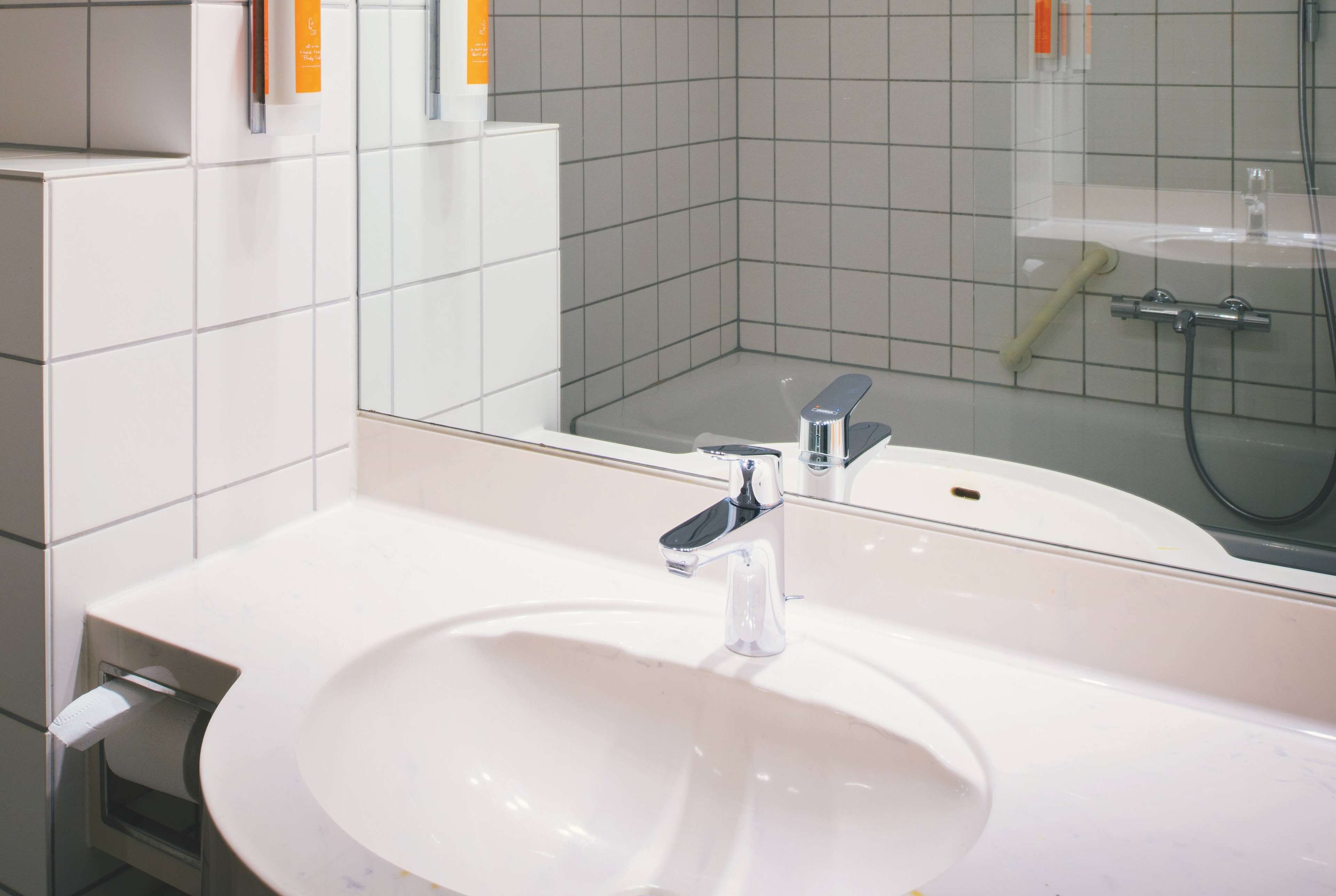A bathroom with a white sink, a mirror, and a shower area.