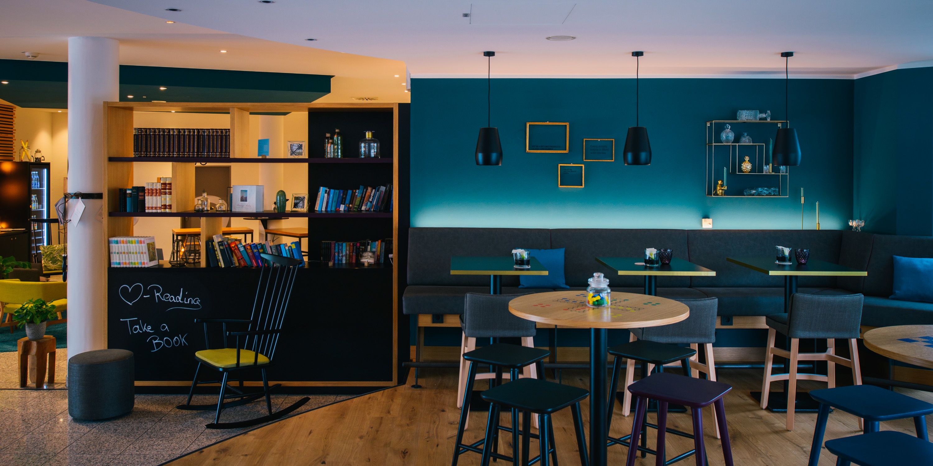 A modern reading area with bookshelves, seating, and a chalkboard sign.