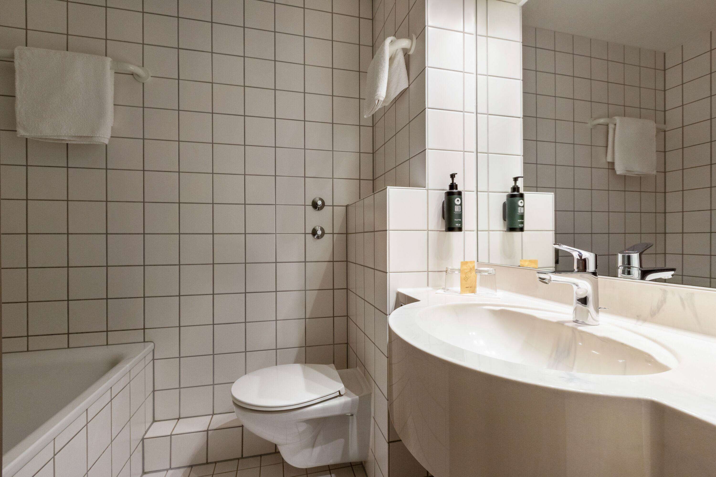 Een moderne badkamer met toilet, wastafel en douche.