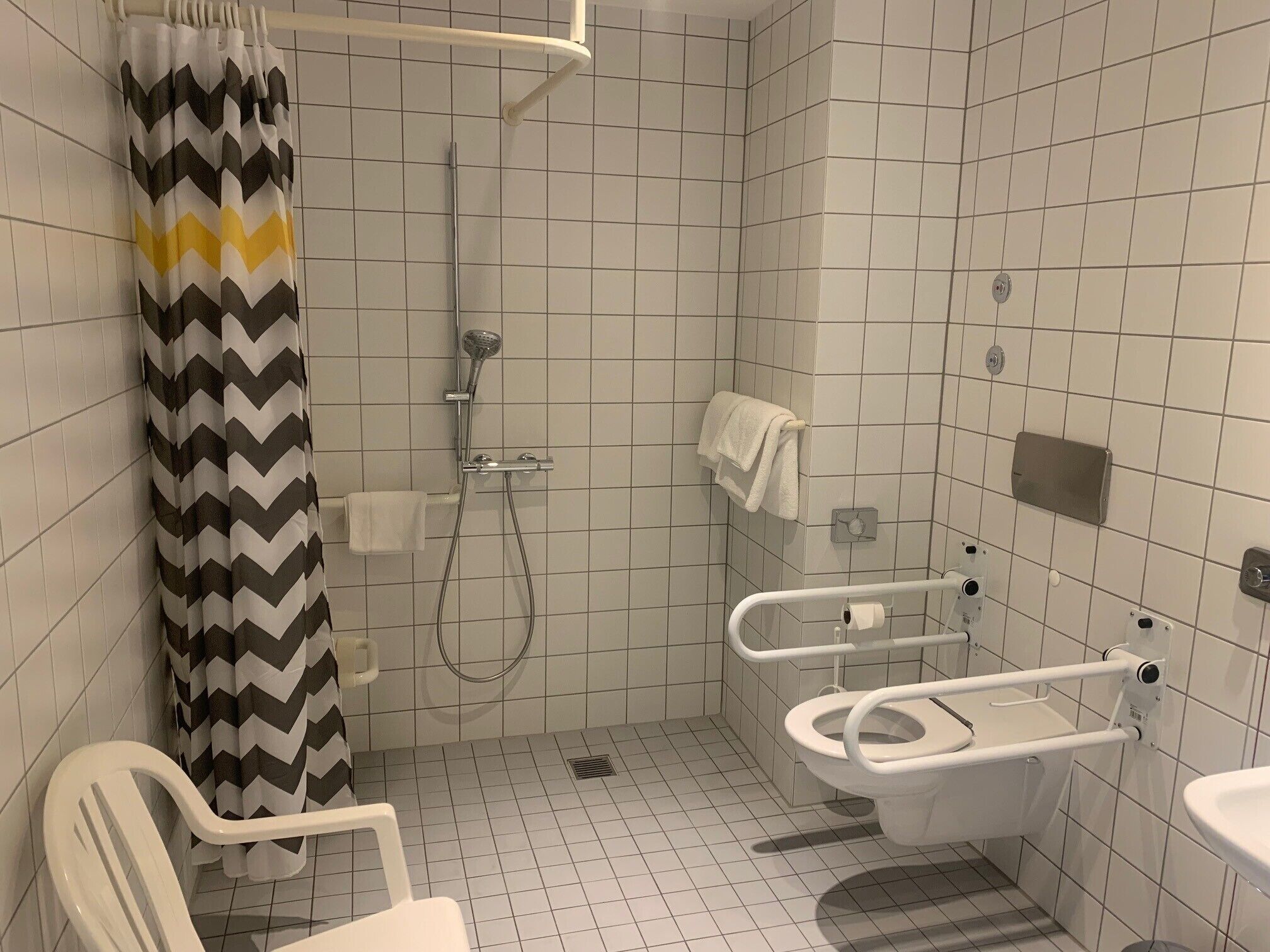 A small, tiled bathroom with a shower, a toilet, and a sink.
