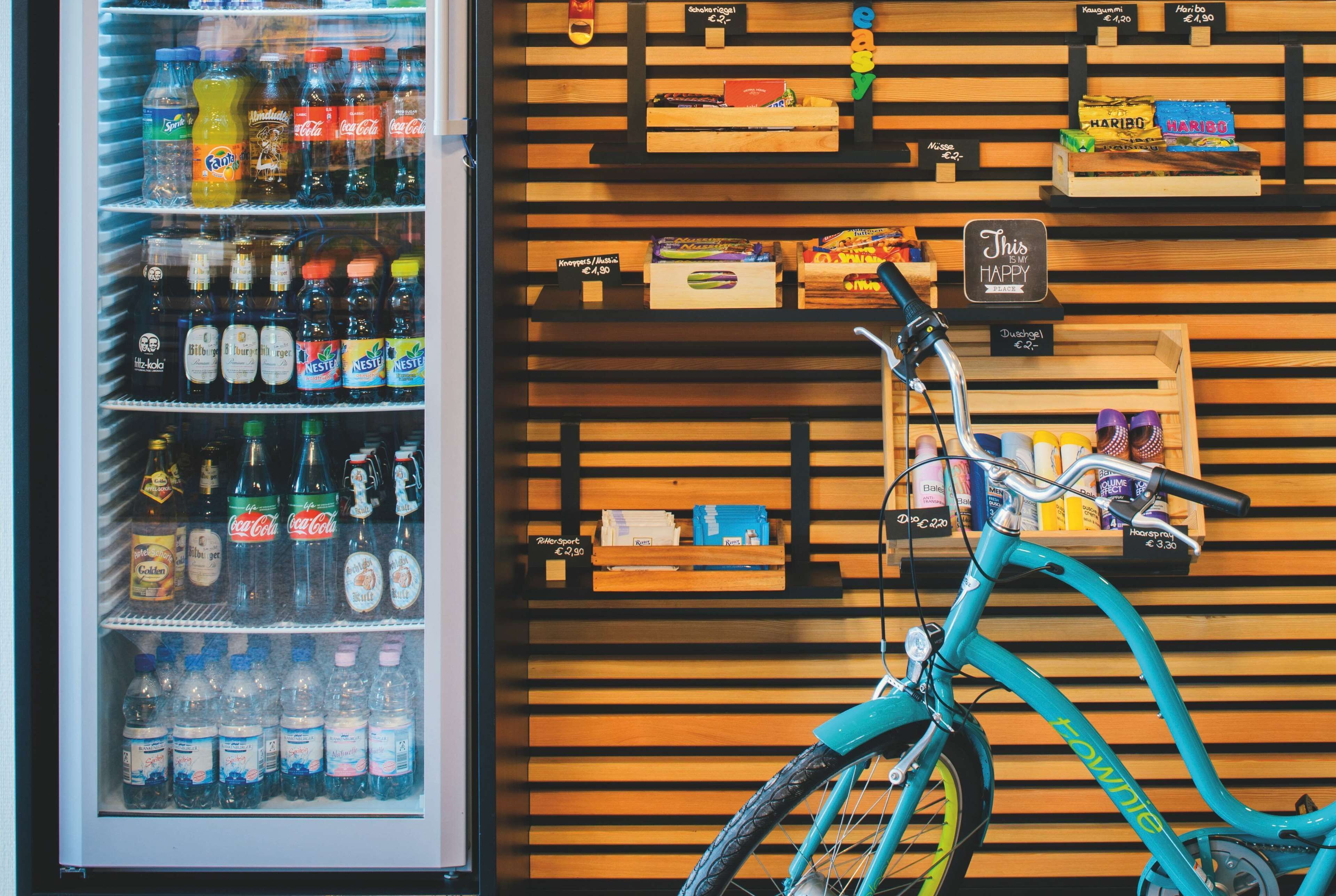 A beverage cooler stocked with various drinks, a bicycle, and shelves with snacks and small items.